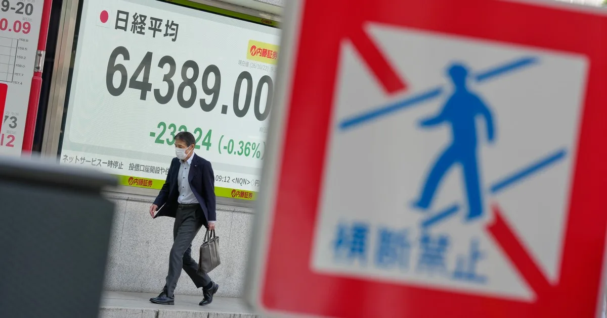 Pedestrian passing a Tokyo stock board showing the Nikkei lower on 22 October 2026